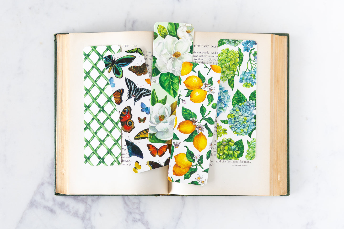 An open book on a marble table with various Hester & Cook Bookmarks inside.