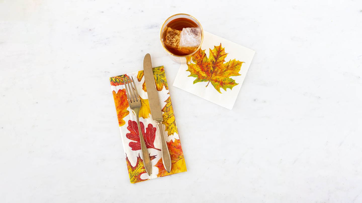 Hester & Cook Fall Foliage Cocktail & Guest Napkins on a marble table with a fork and knife and glass of iced tea.