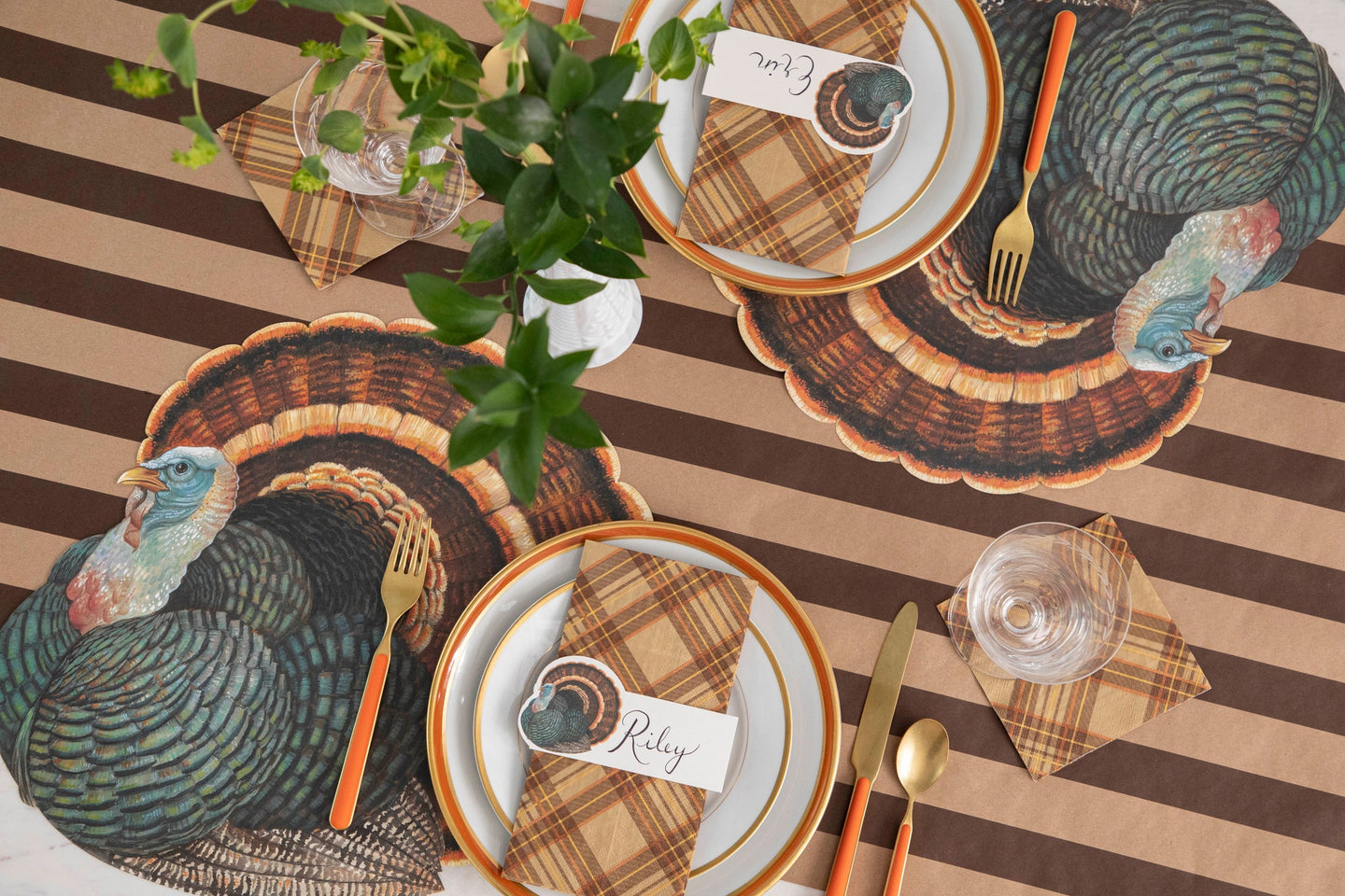 A Thanksgiving table setting featuring Autumn Plaid Napkins, Die-cut Heritage Turkey Placemats, and Heritage Turkey Place Cards on the Kraft Brown Classic Stripe Runner.