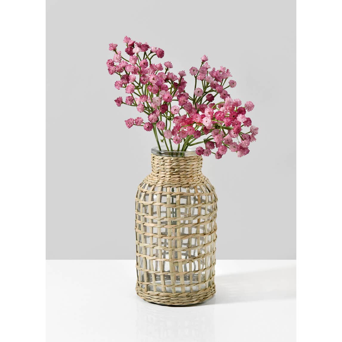 Woven vase with pink flowers on a white background.