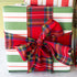 Stack of gift boxes wrapped in red, green, and white stripes with a plaid bow.