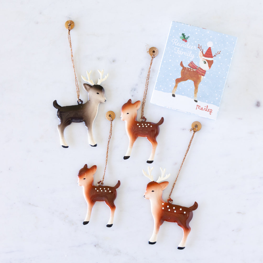 Set of four deer-shaped ornaments with a box featuring a deer illustration on a snowy background with the text "Reindeer Family" by Maileg.