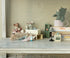 Miniature toys and furniture on a wooden surface with a patterned wall in the background. 