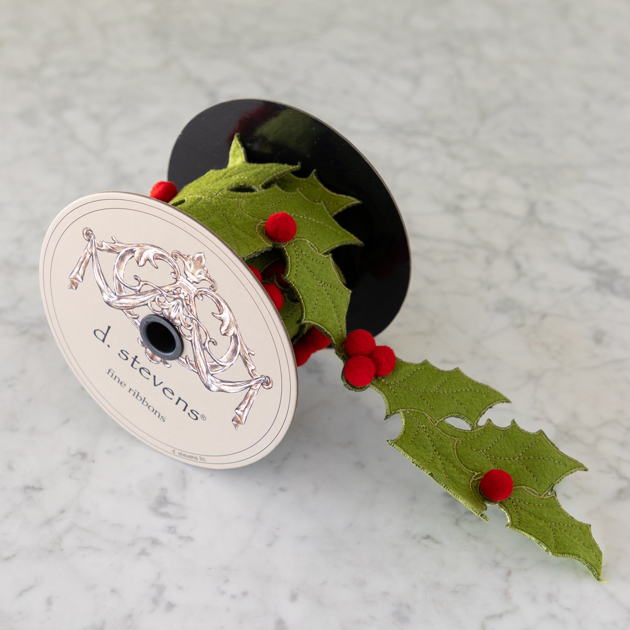 Spool of green ribbon with red berries and &