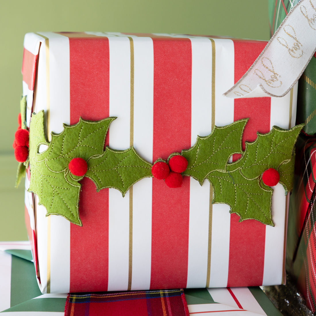 Christmas gift wrapped in red and white striped paper with holly decorations.