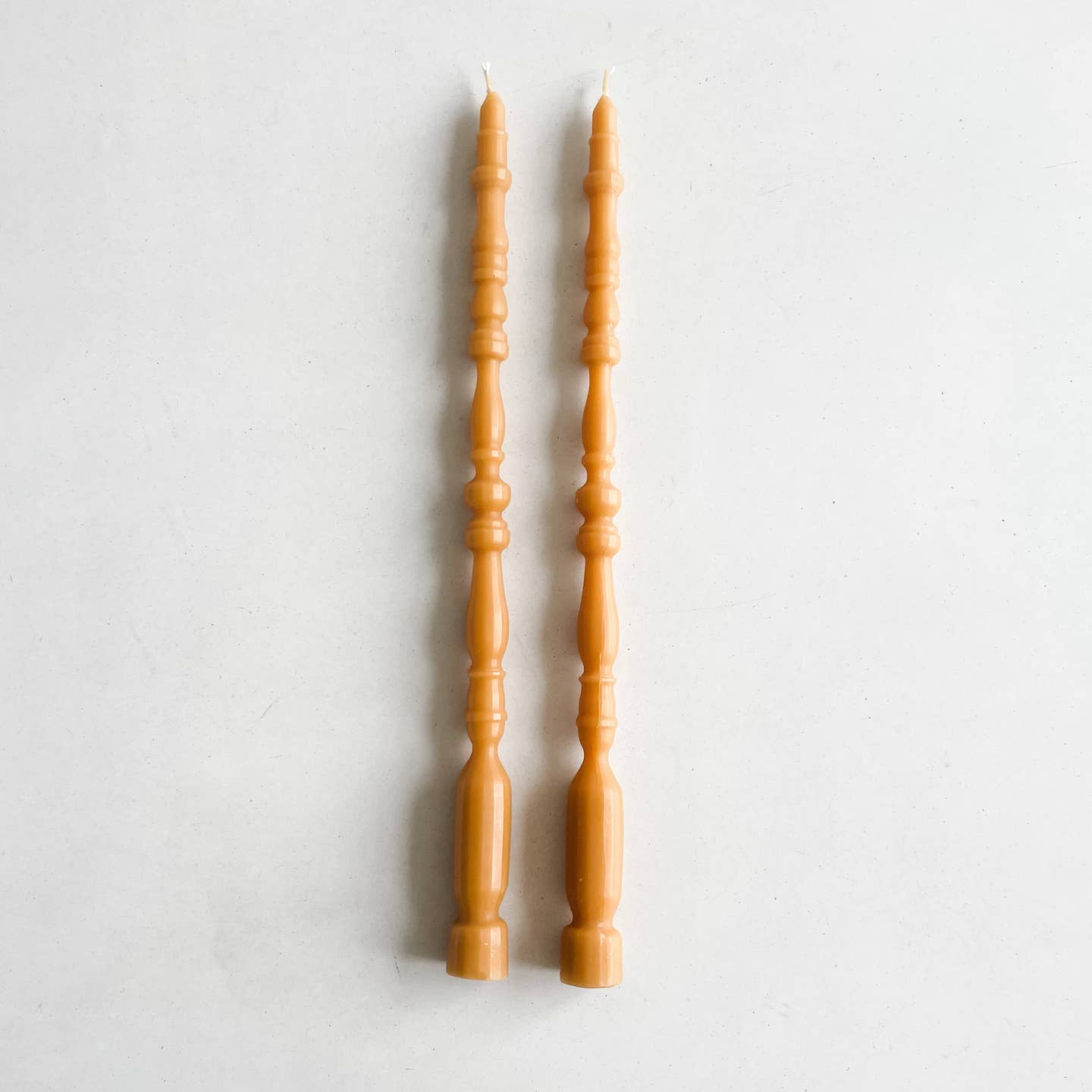 2 taper candles shaped like table spindle legs in oro.