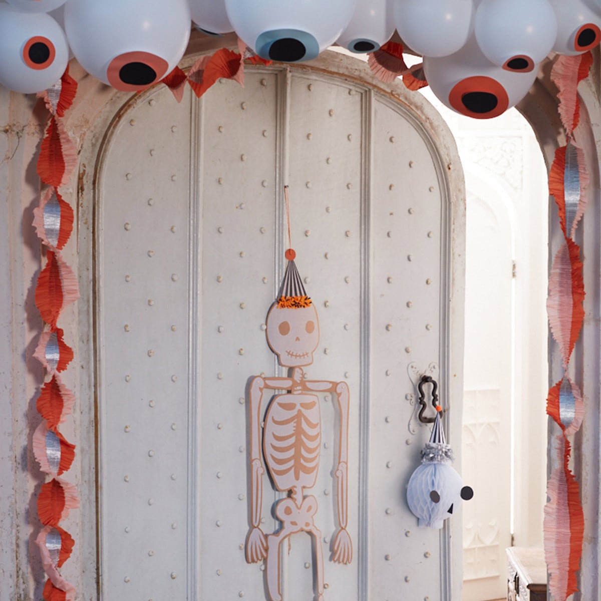 Decorative skeleton hanging on a door with Halloween-themed decorations.
