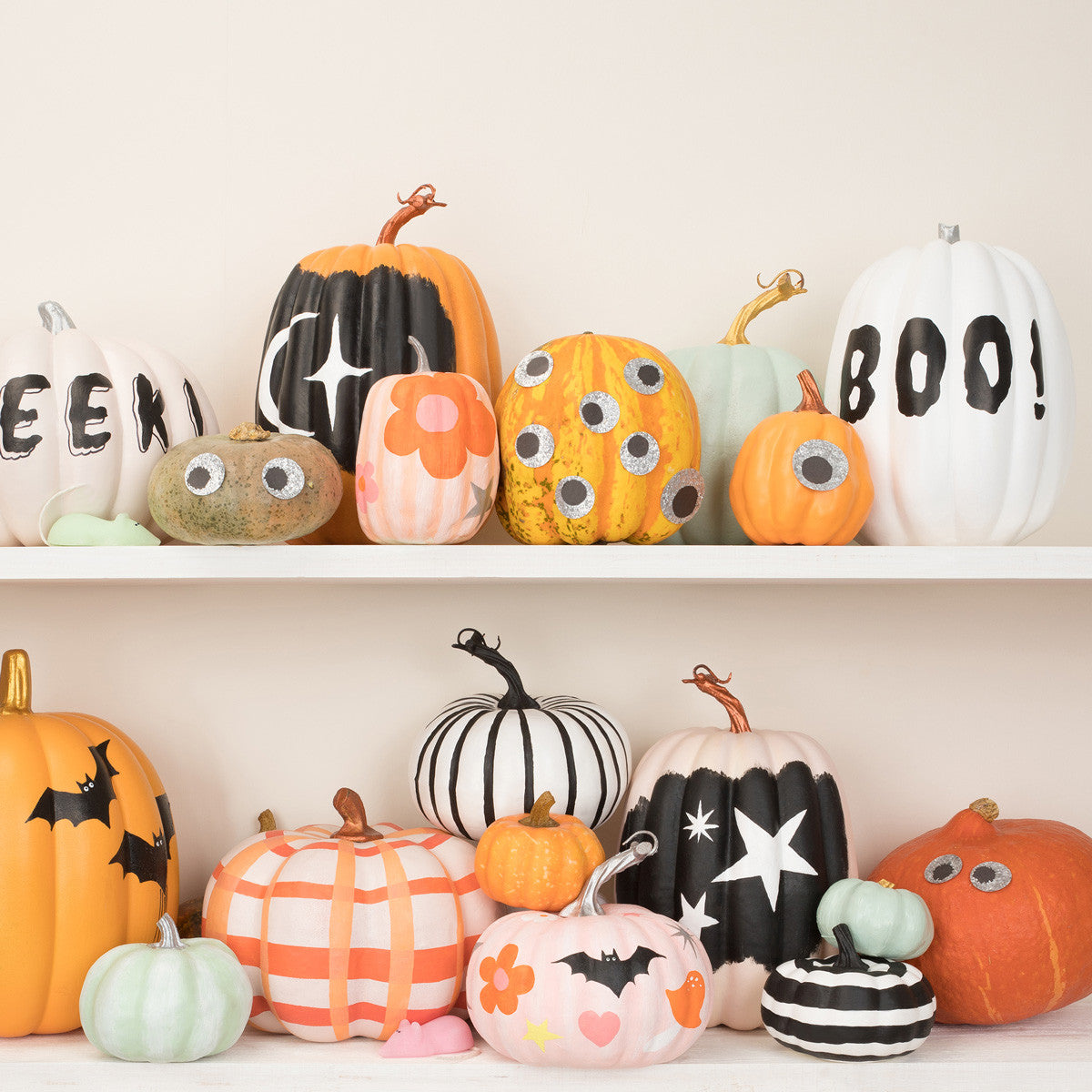 Decorative pumpkins with various designs on a white shelf.