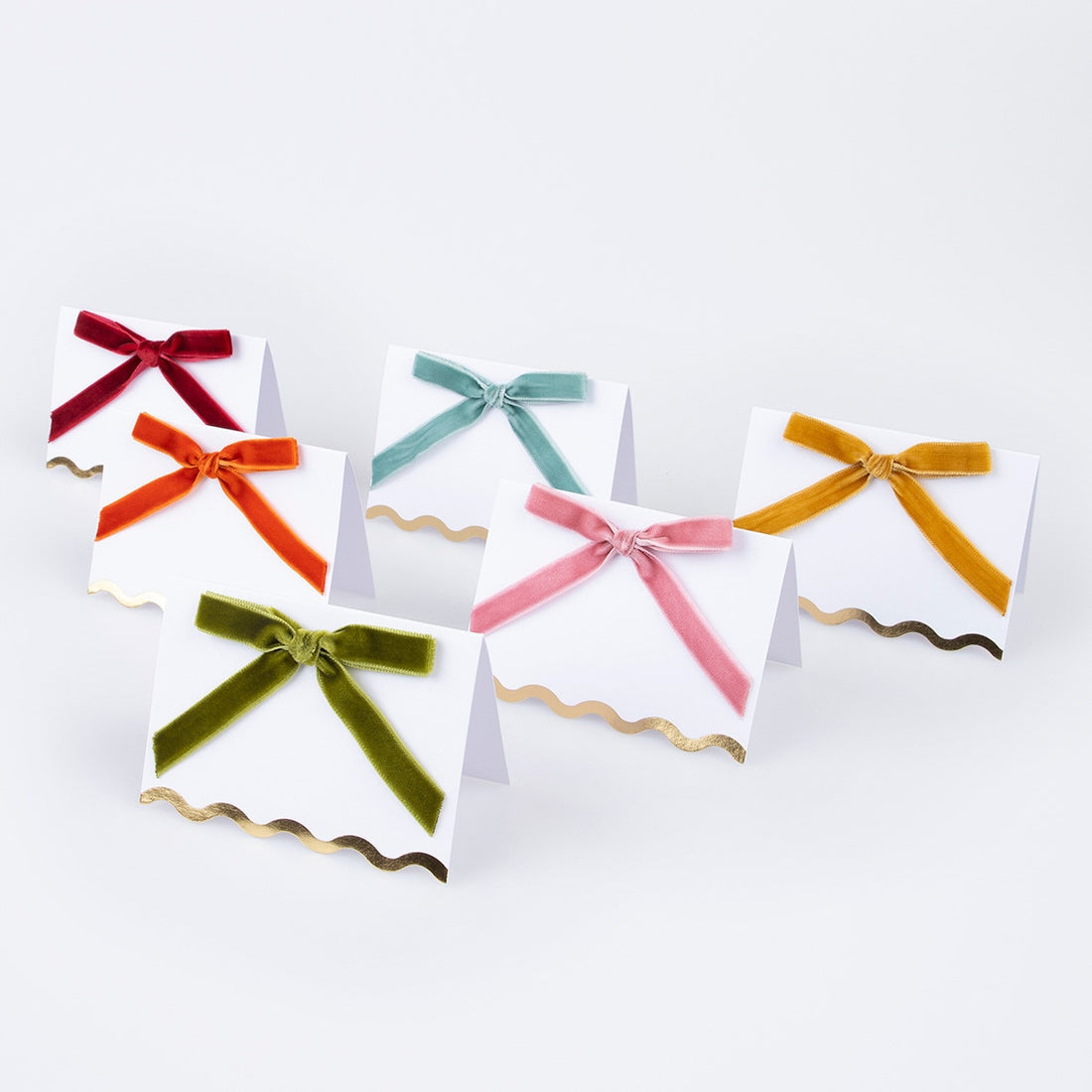 6 Place cards with 6 different colored velvet bows - golden yellow, burnt orange, teal blue, dusty pink, olive green and deep red.  Each has a scalloped edge and shiny gold foil details.