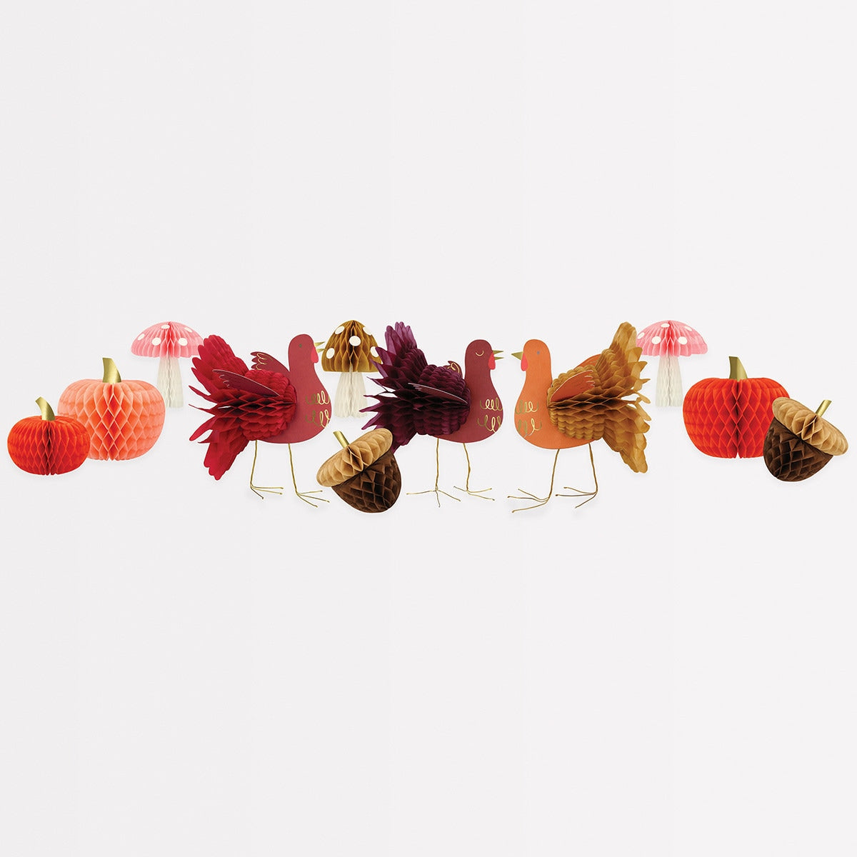 A variety of tissue paper honeycomb decorations with vintage designs including orange and peach pumpkins, mushrooms, acorns, and turkeys in shades of maroon and red.