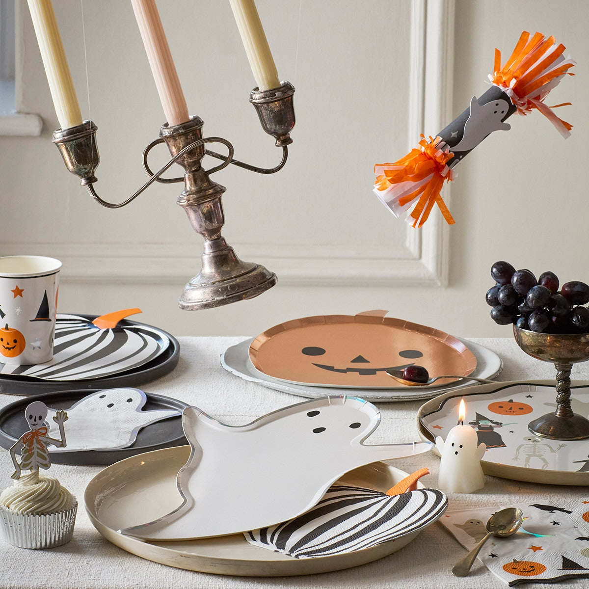 Halloween-themed table setting with ghost plates, candles, and decorative items.