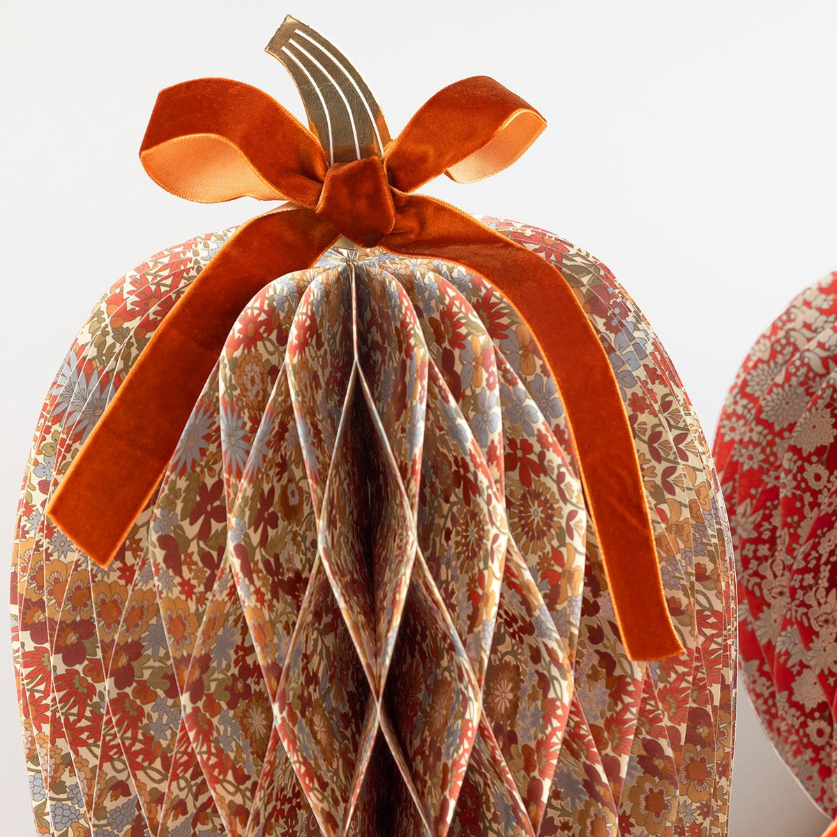 Decorative pumpkin with floral pattern and orange ribbon on a white background