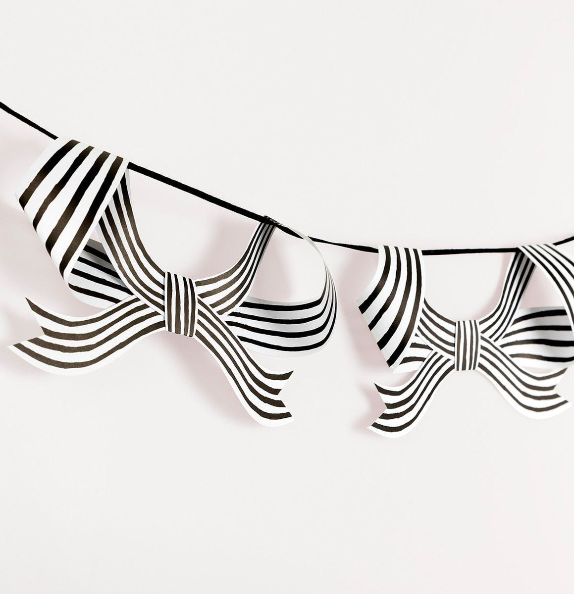 Decorative string with black and white stripe bows hung on it on a white background.