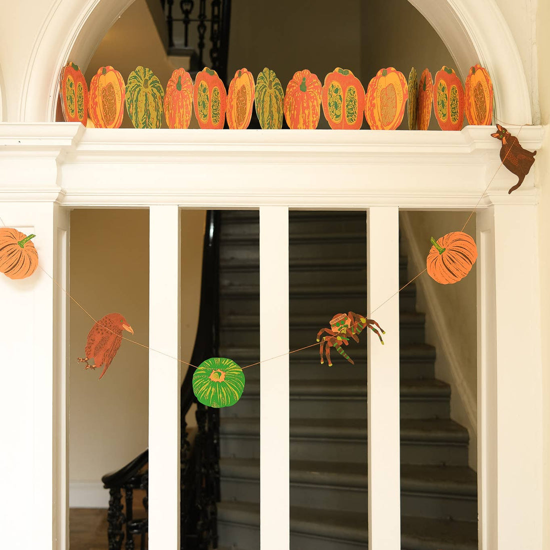 In bold greens and bright oranges, this garland features all the traditional images of Halloween - cats, ravens, spiders and pumpkins, shown hanging in a doorway.