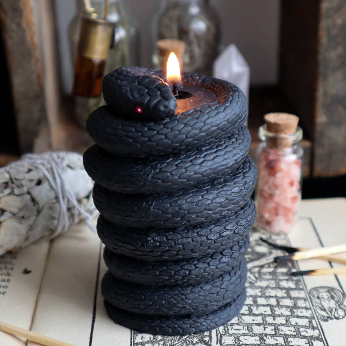Pillar candle that looks like it has a black snake wrapped around it. 