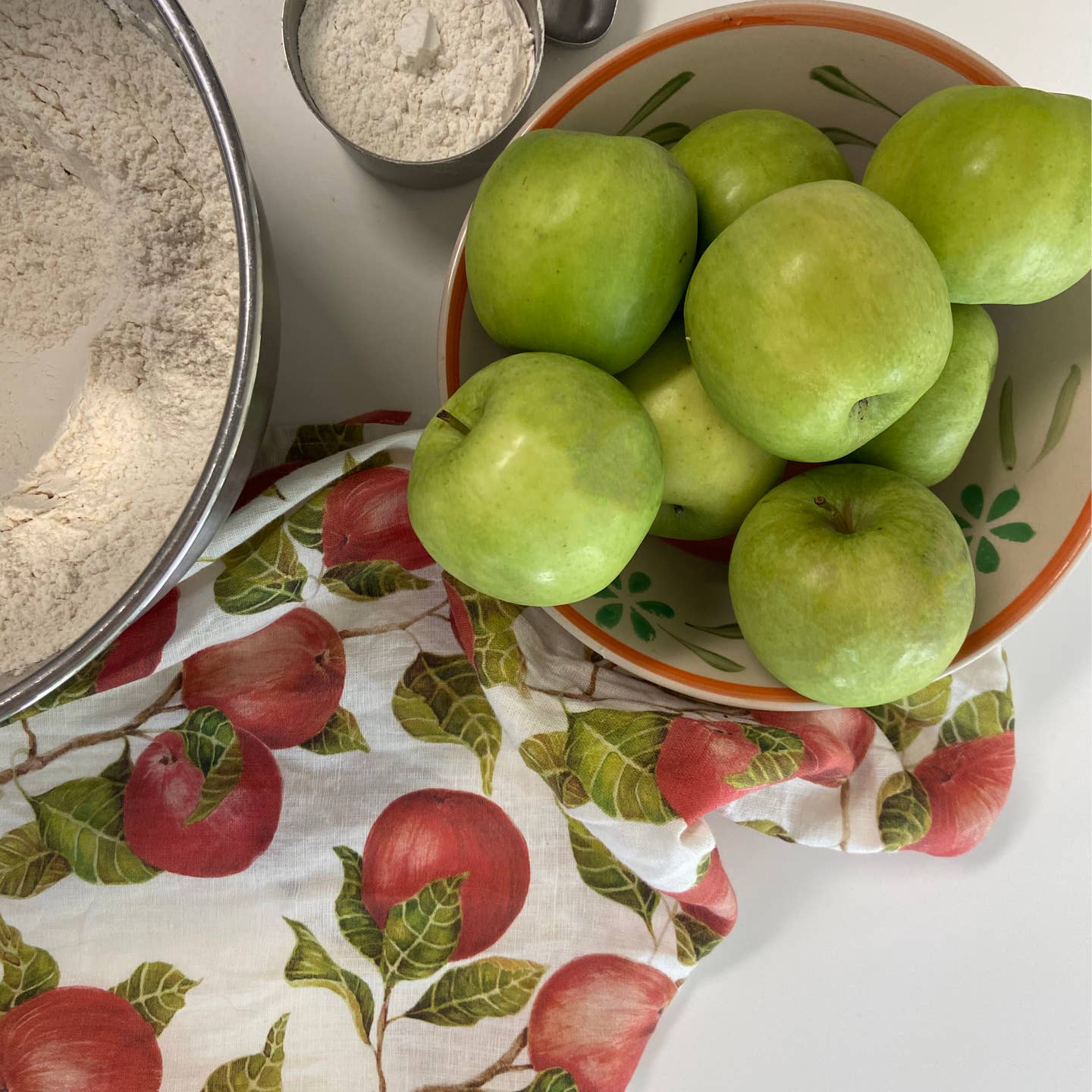Bowl of green apples on a tablecloth with apple pattern