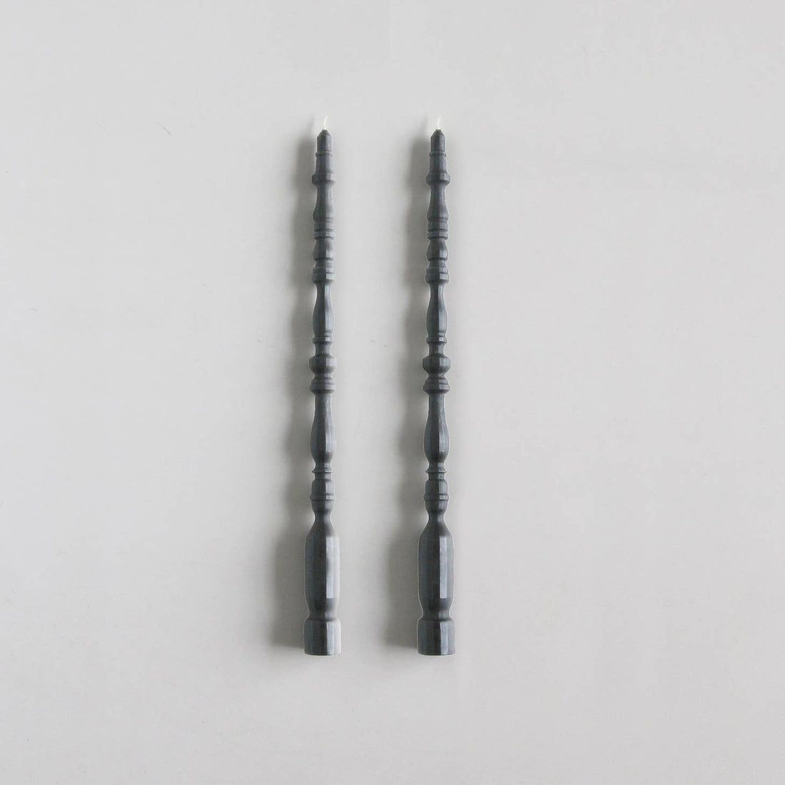 2 taper candles shaped like table spindle legs in slate. 
