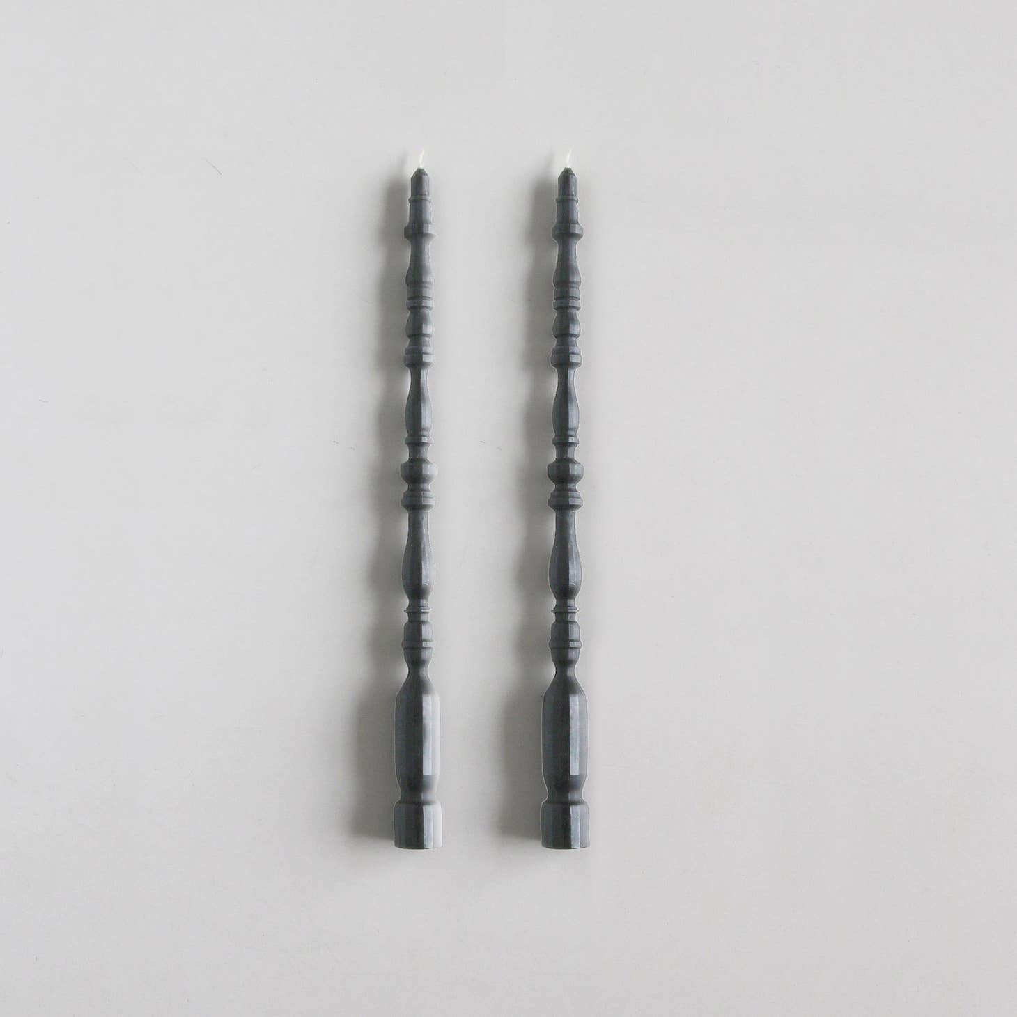 2 taper candles shaped like table spindle legs in slate. 