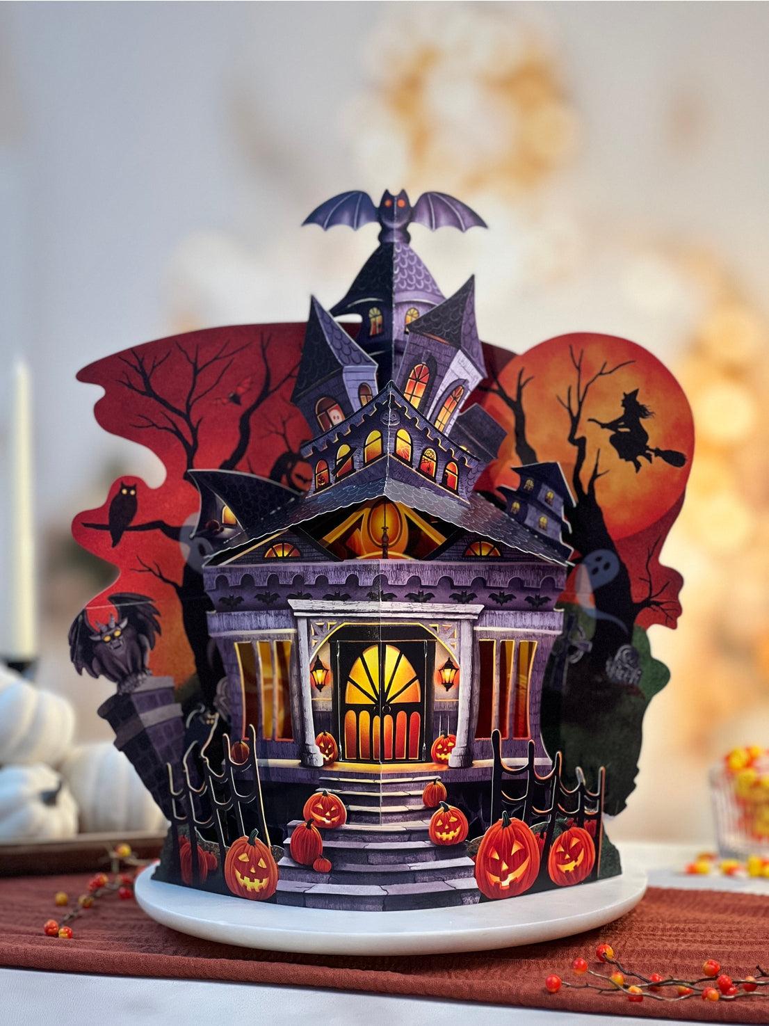 Halloween-themed pop-up house with pumpkins and bats on a decorative table.