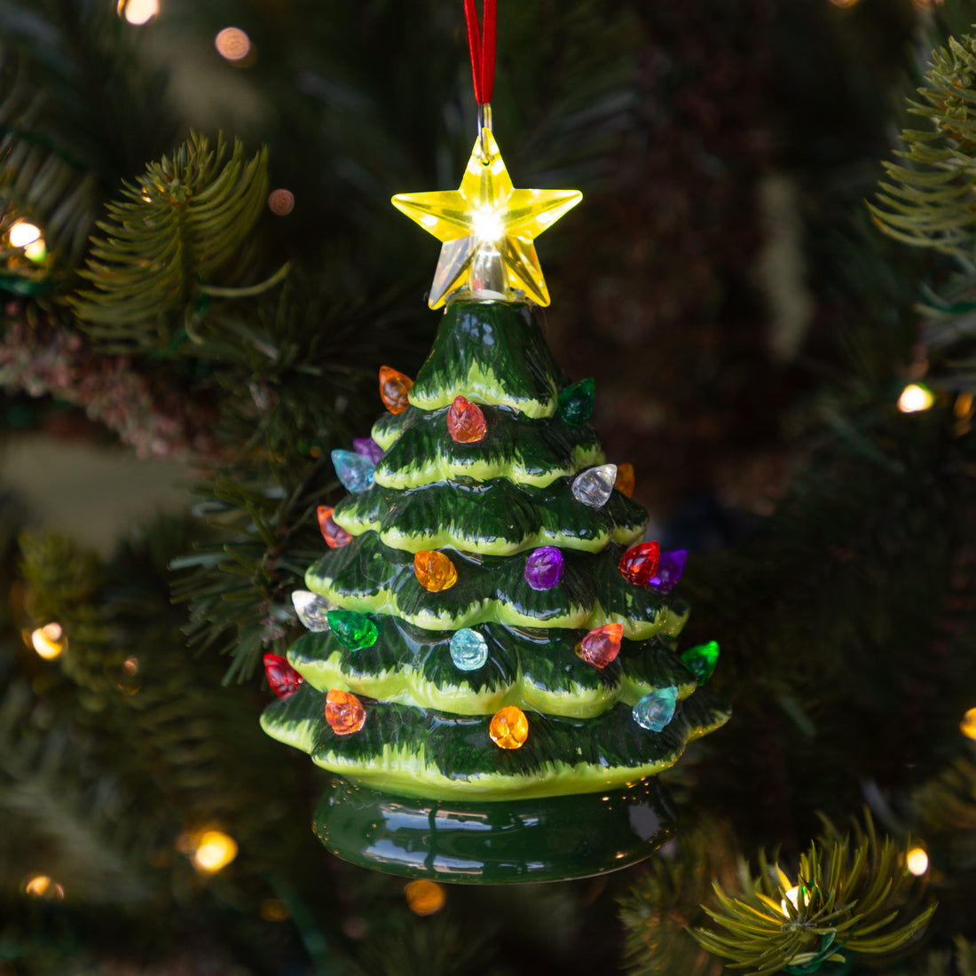 Vintage Lighted Christmas Tree Ornament featuring colorful lit bulbs and a lit yellow star on top, hanging on a lit Christmas tree.