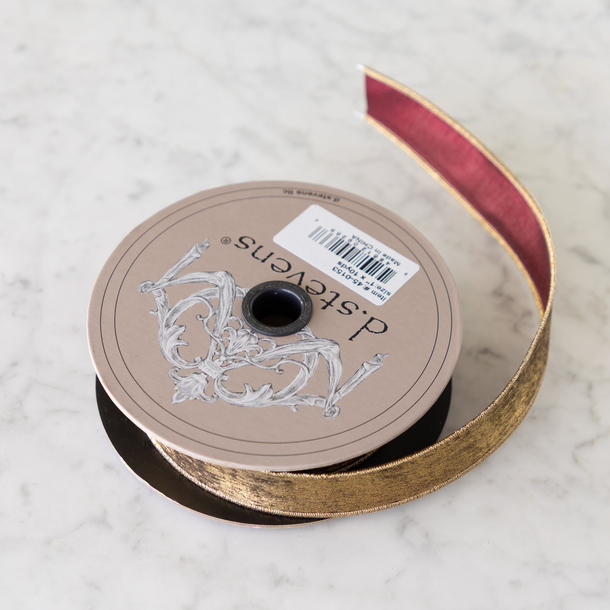 Spool of ribbon with a decorative label on a marble surface.