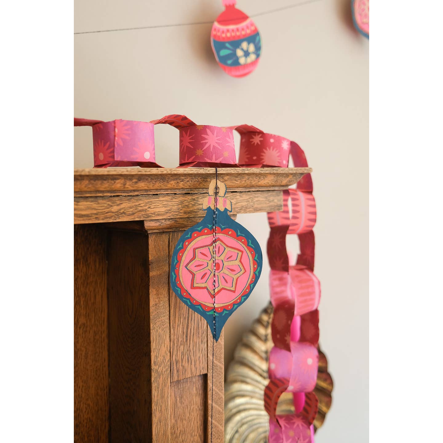 Decorative pink and blue hanging ornament garland on a wooden surface
