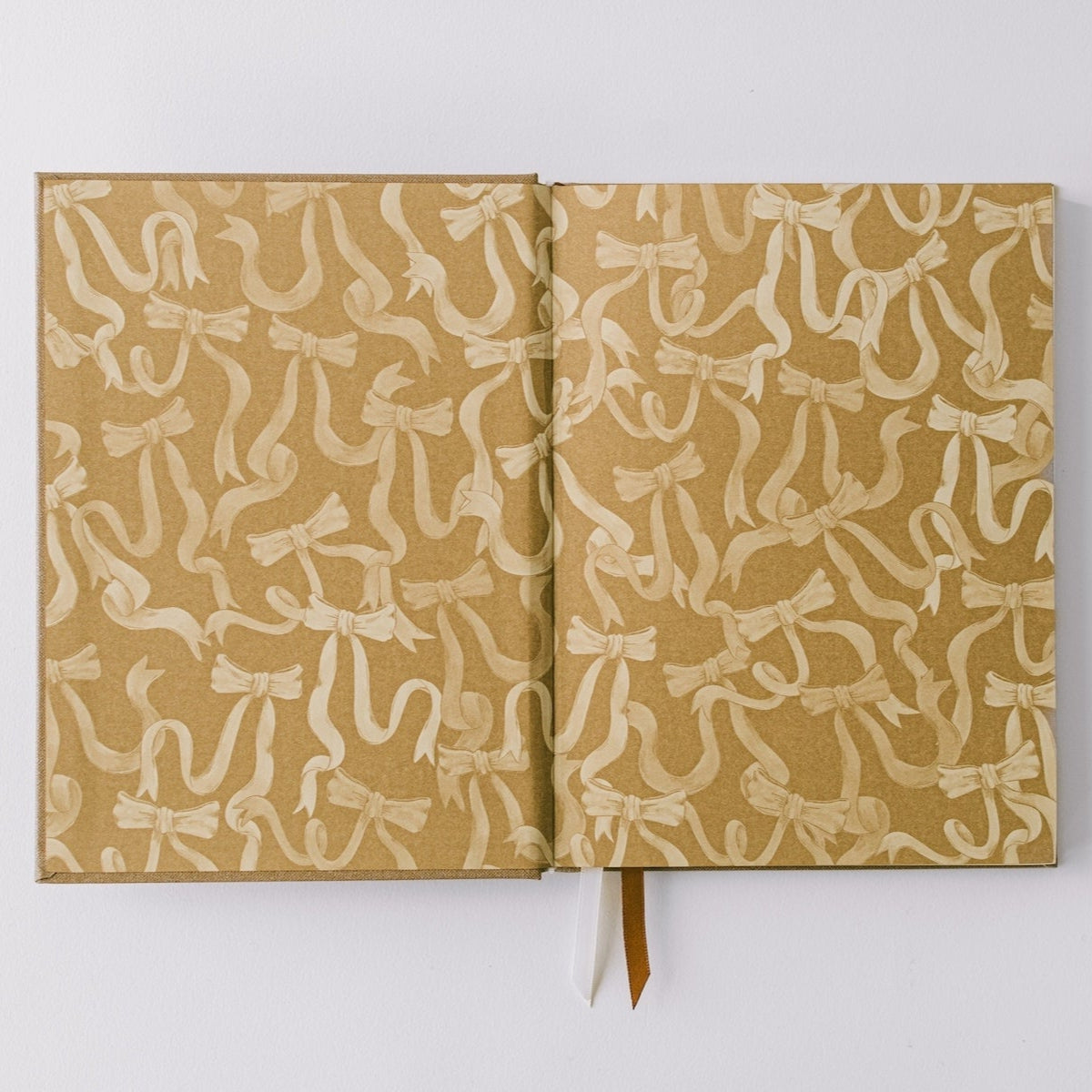 Notebook by Good Juju with gold detailing depicting a bow. 