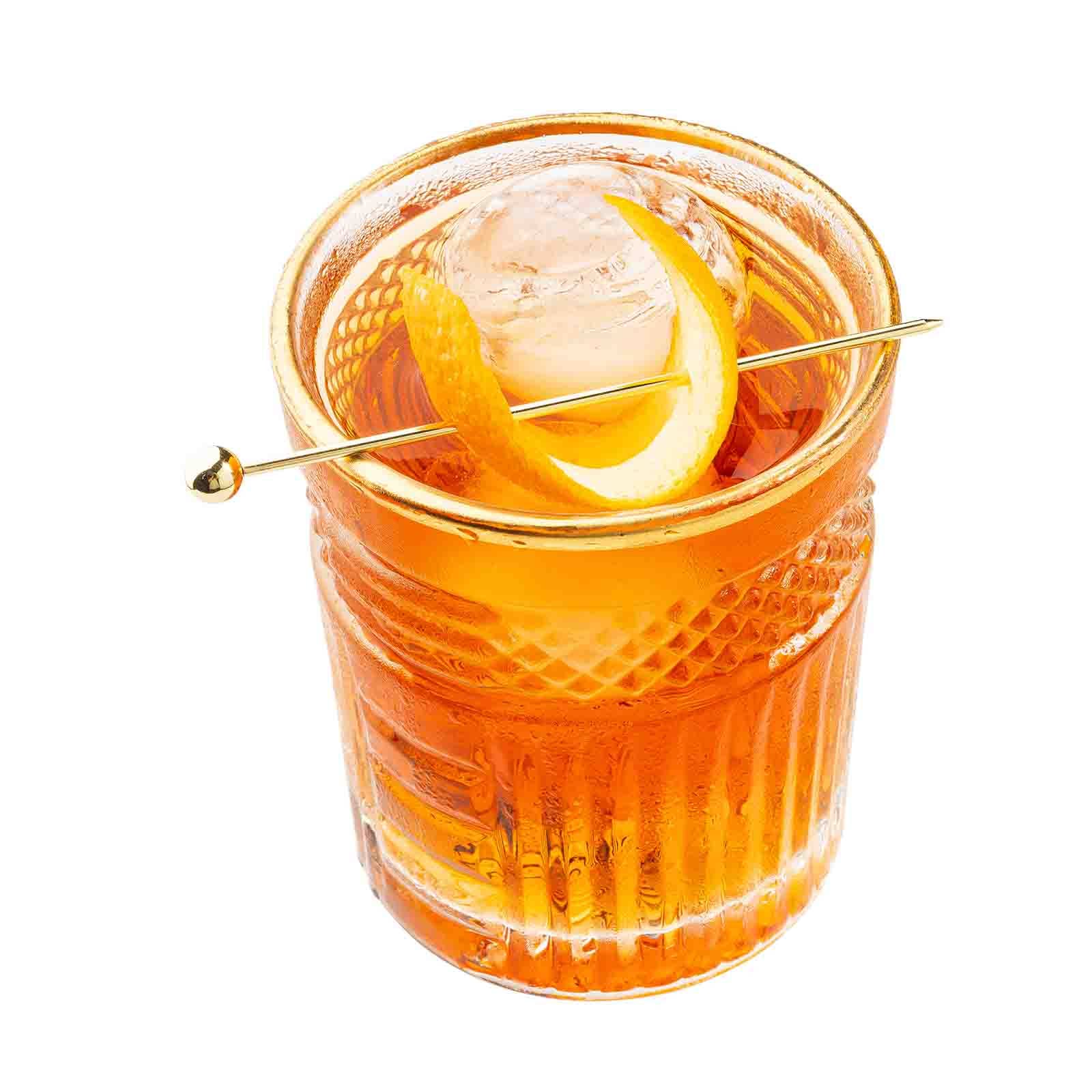 The Gold Cocktail Pick piecing an orange peel on top of a cocktail.