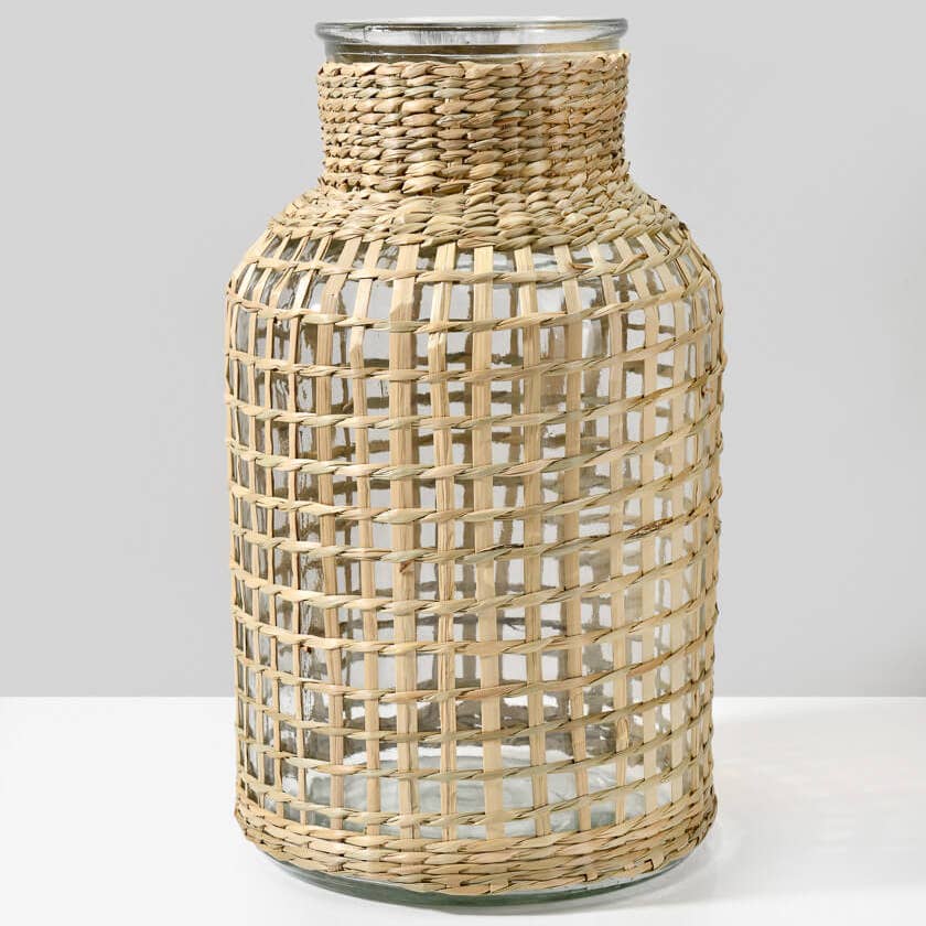 Glass vase with woven rattan cover on a white background.