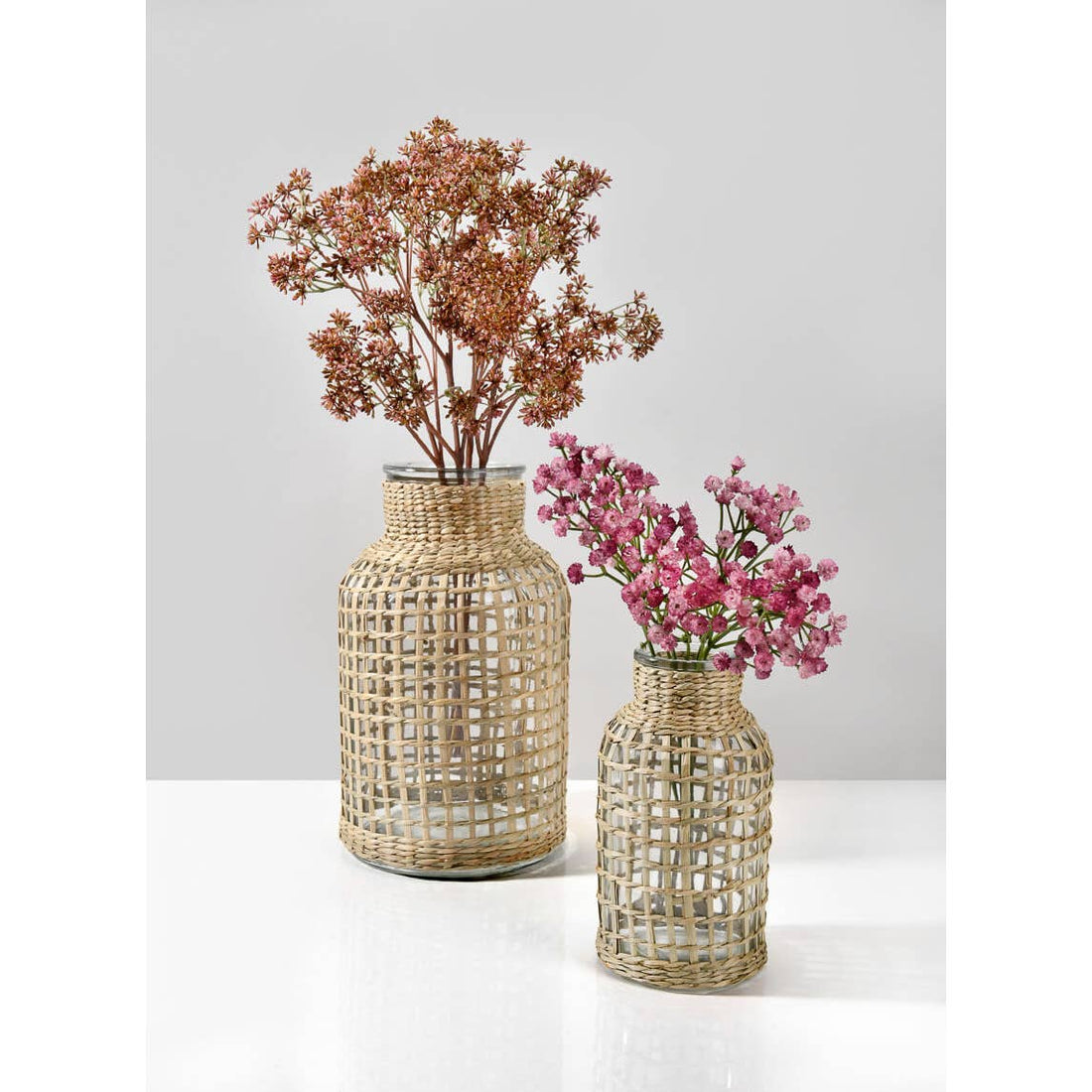 Two woven vases with flowers on a white background.