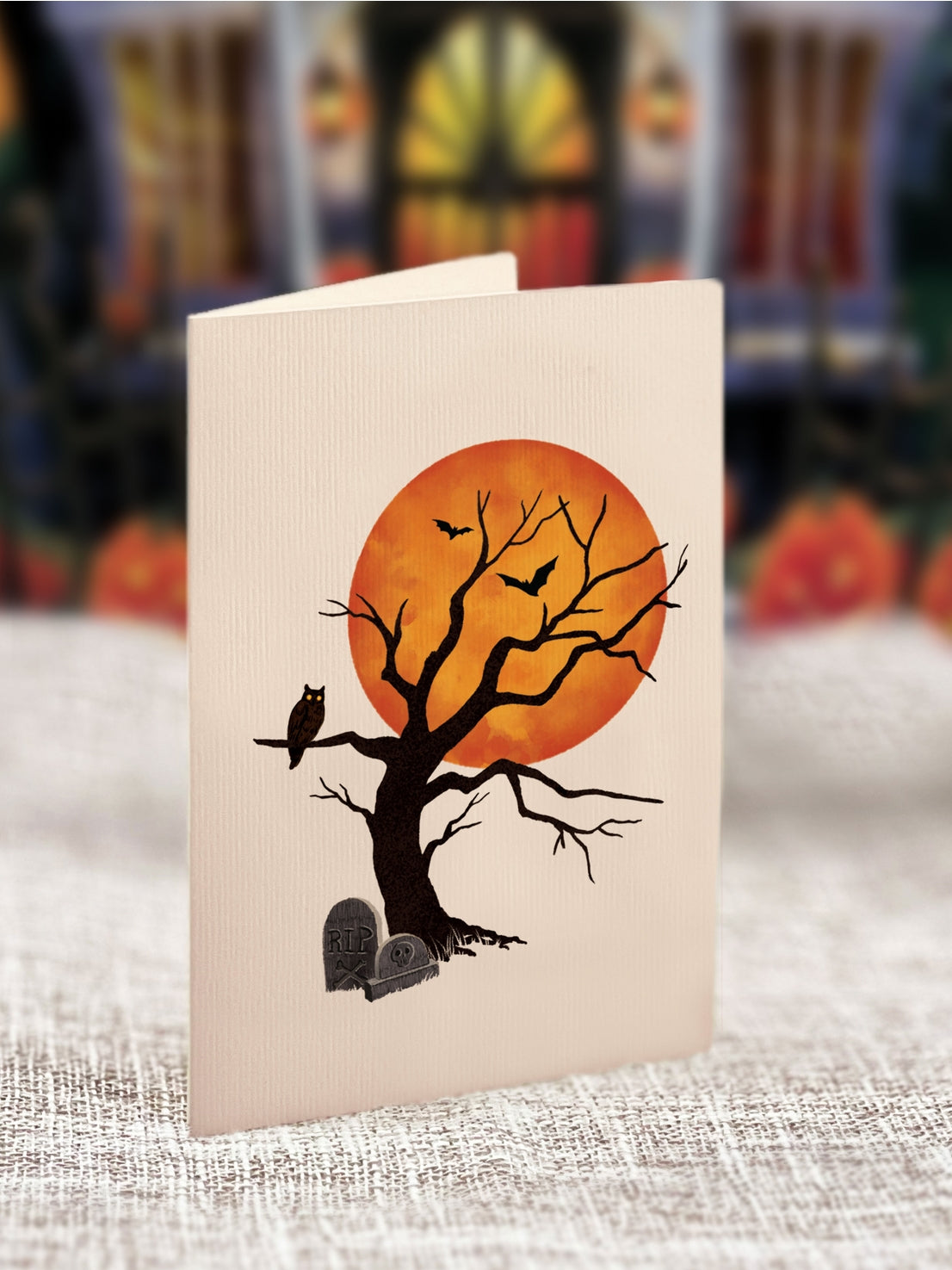 Halloween-themed card with tree, owl, and moon design on a textured surface.