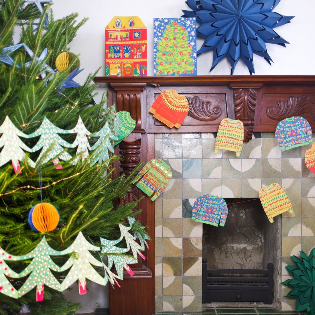 A colorful garland of Christmas sweater designs hanging indoors, displayed around a fireplace and above a mantel.
