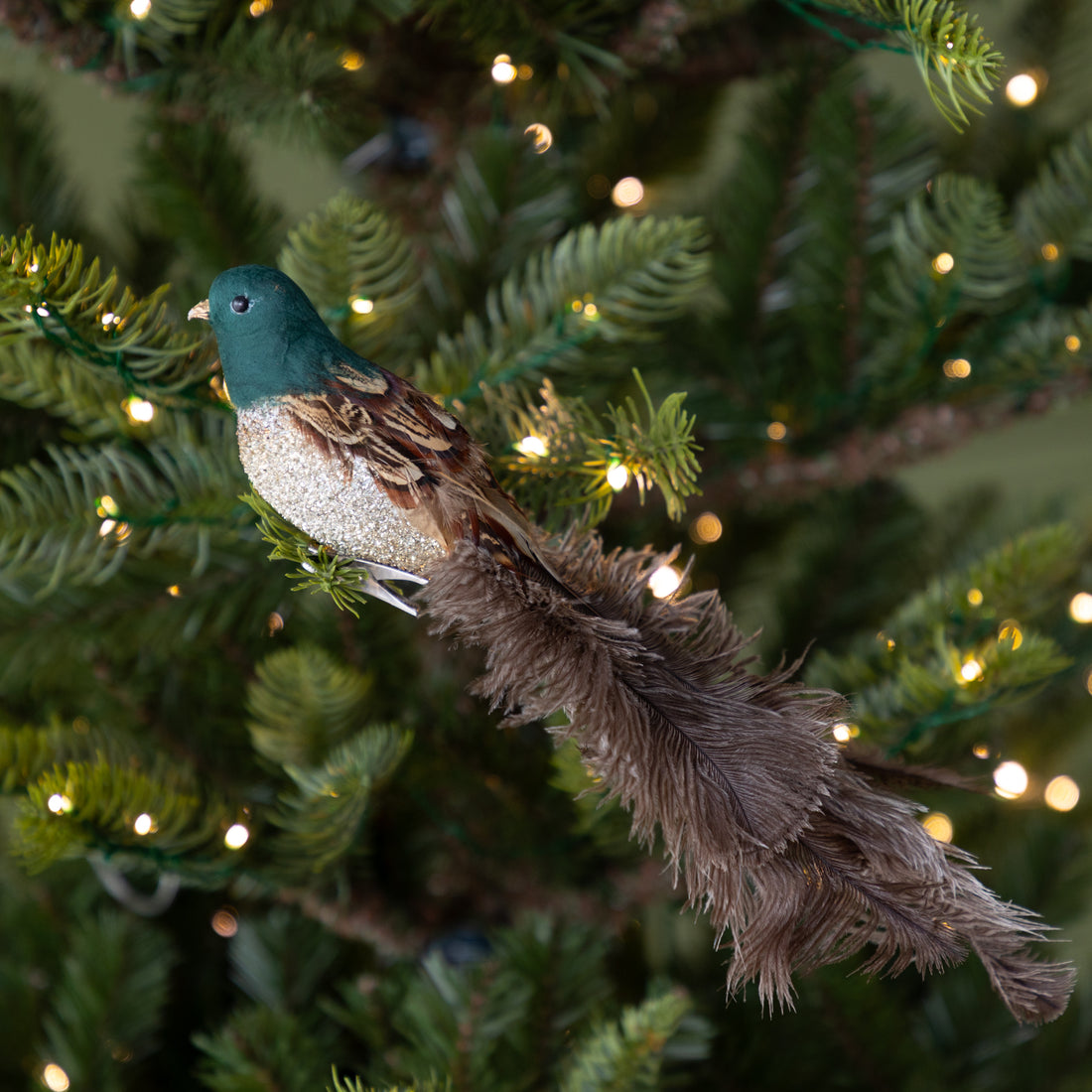 Decorative bird ornament on a Christmas tree with lights.