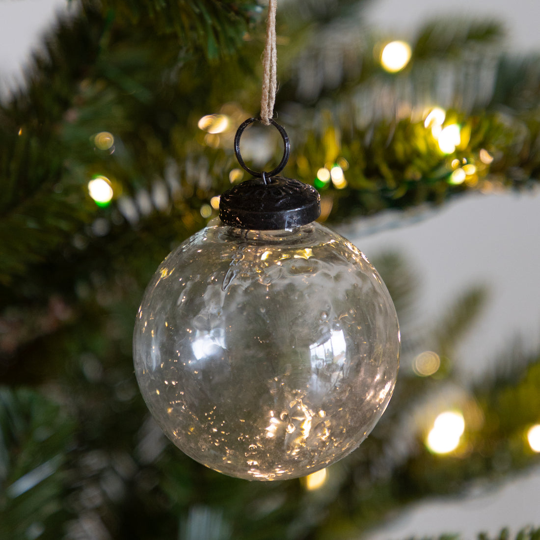 Glass Ball Ornament hanging on a lit Christmas tree.