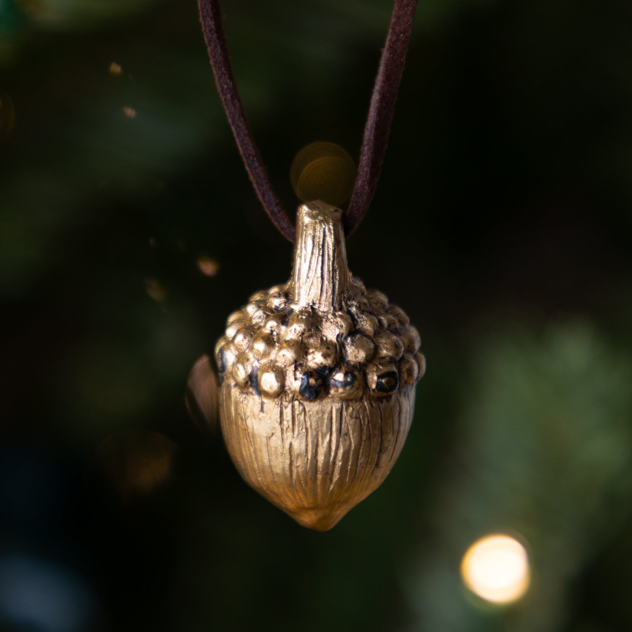 Gold acorn-shaped ornament hanging on a tree.