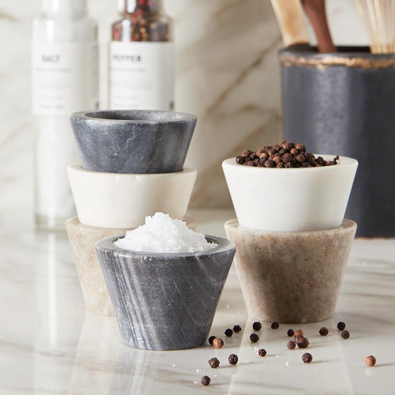 Set of small stone bowls with different contents on a light surface.