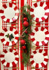 A set of red and white scalloped paper plates with gold foil edges, arranged on a table to mimic a festive dinner setting, decorated with candy canes, pine branches, and holiday ornaments.