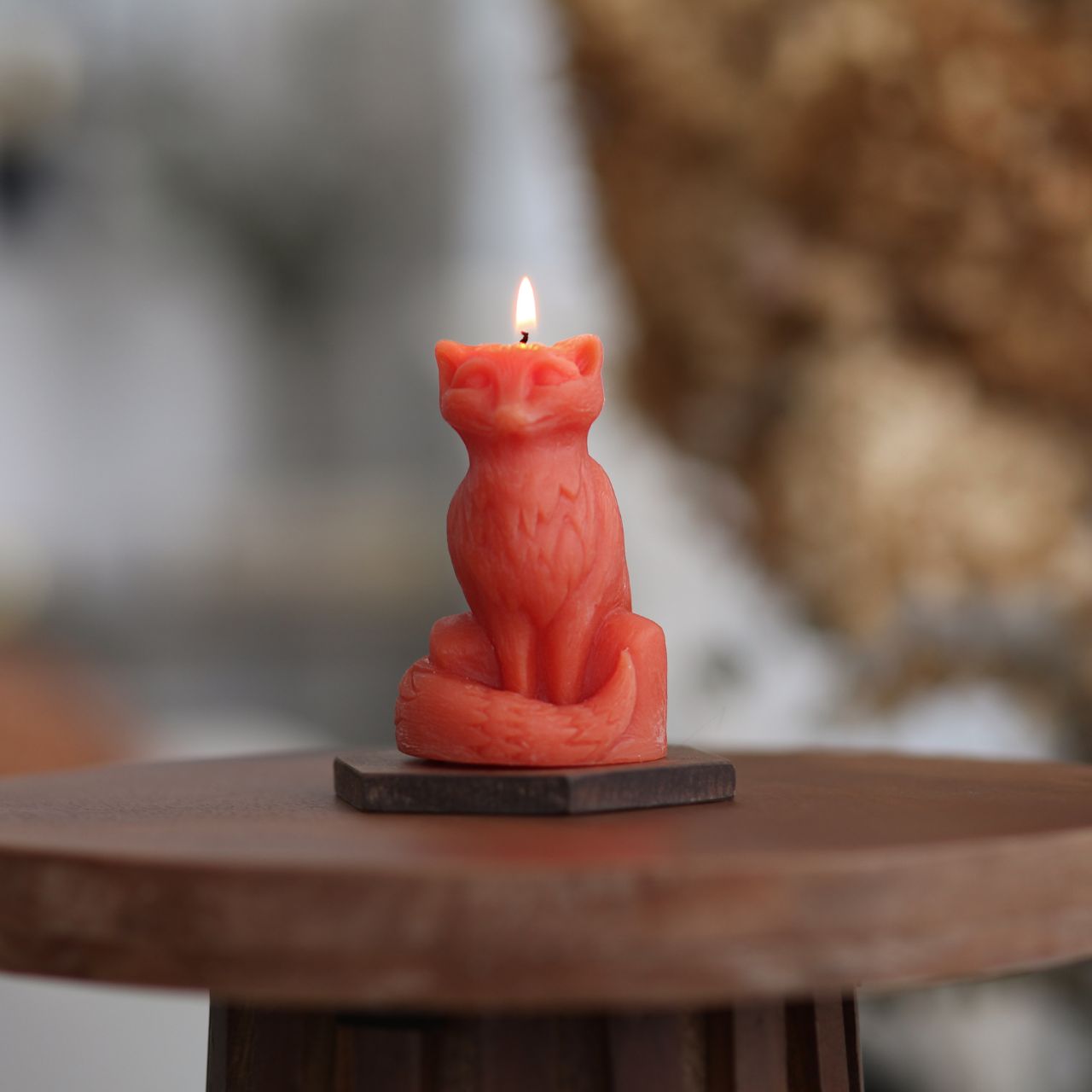 Red candle shaped like a fox on a wooden surface with a blurred background