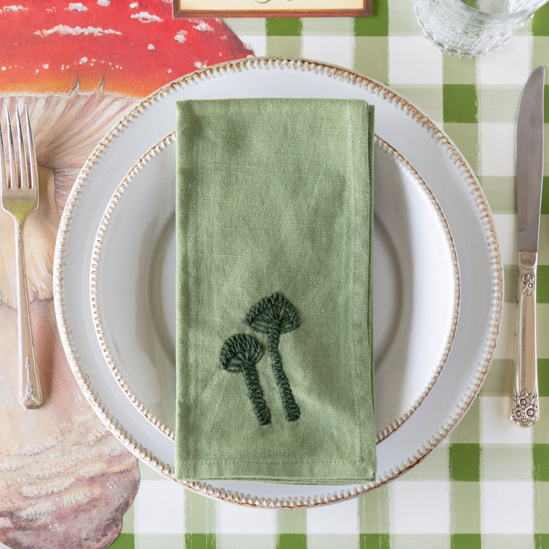 Mushroom-themed place setting with the Embroidered Mushroom Napkin resting on the plates.