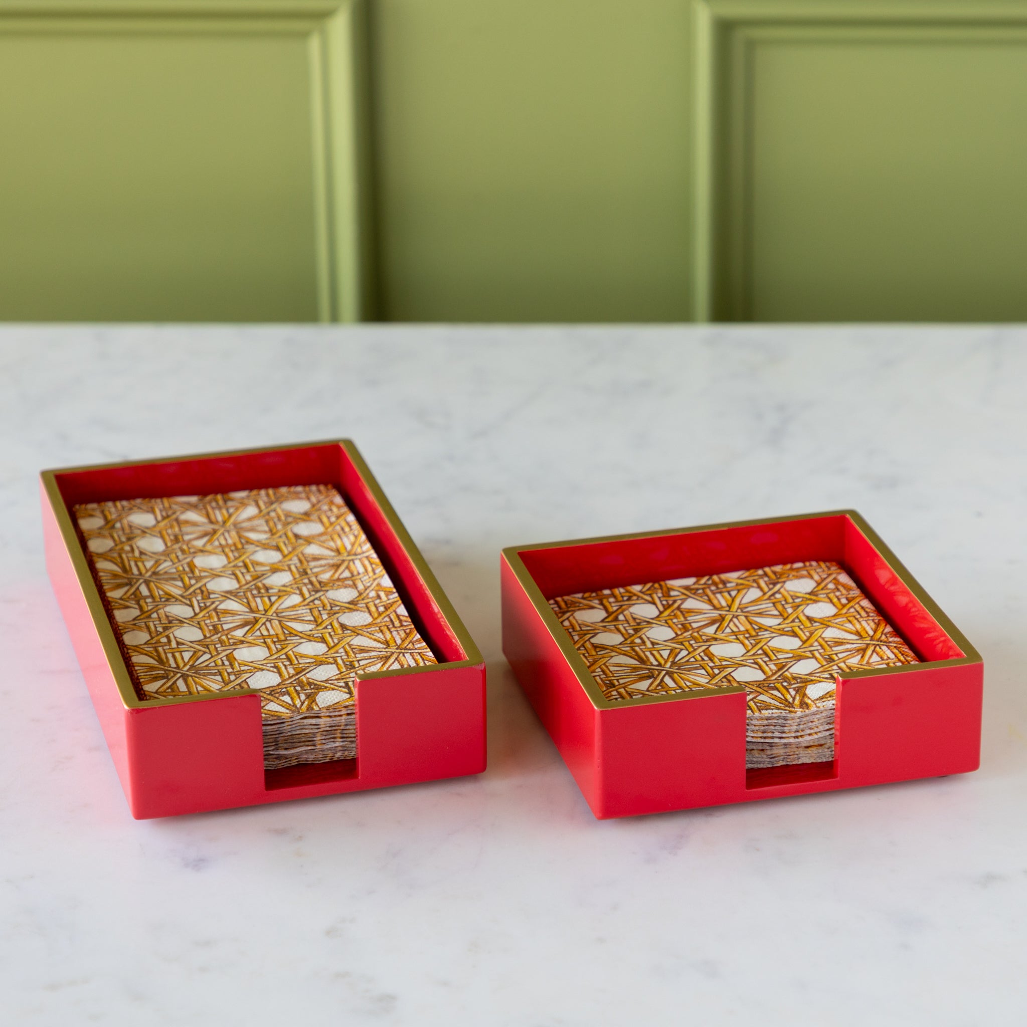 Two Beverage Napkin Holders in red with gold trim holding Rattan Weave Napkins.