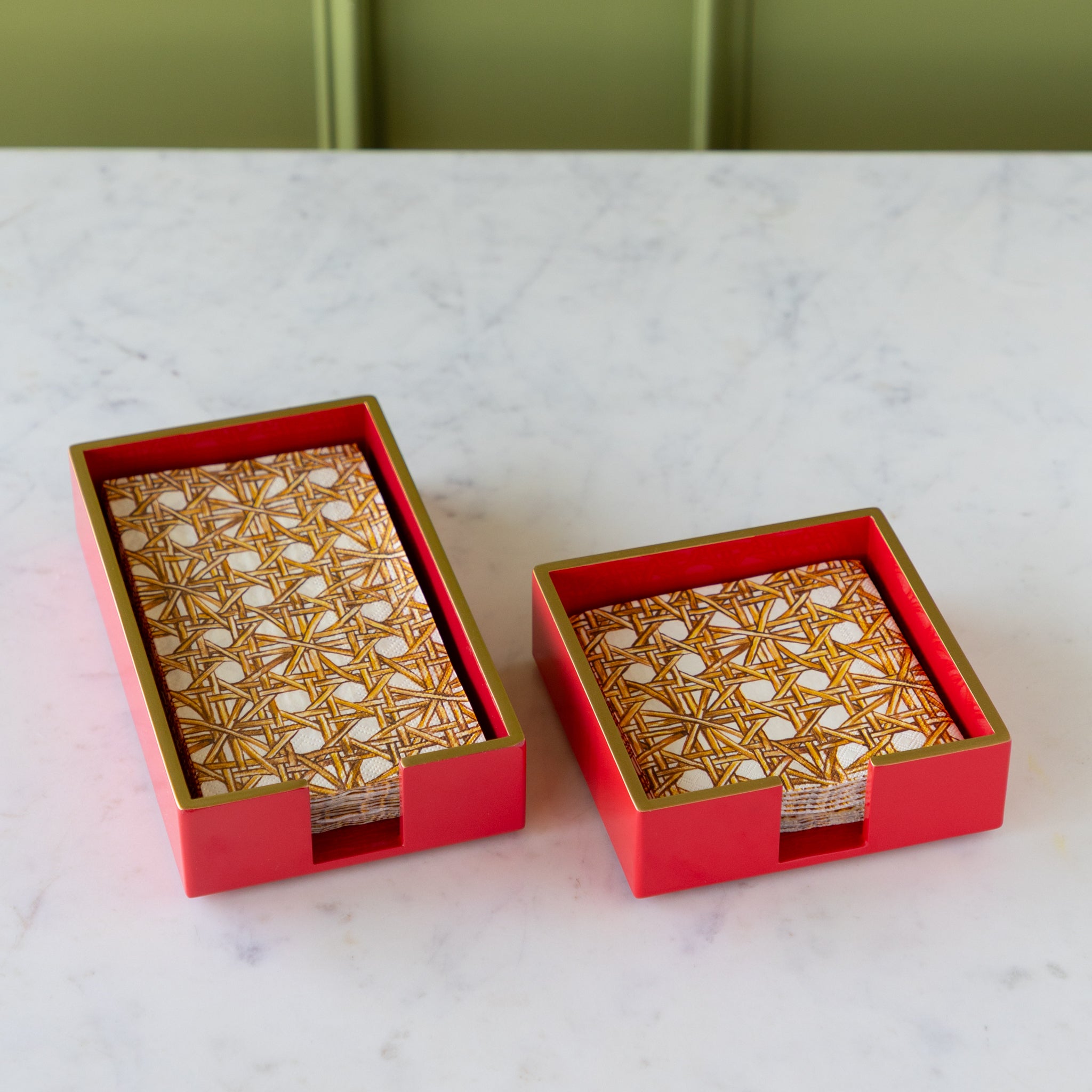 Two Beverage Napkin Holders in red with gold trim holding Rattan Weave Napkins.