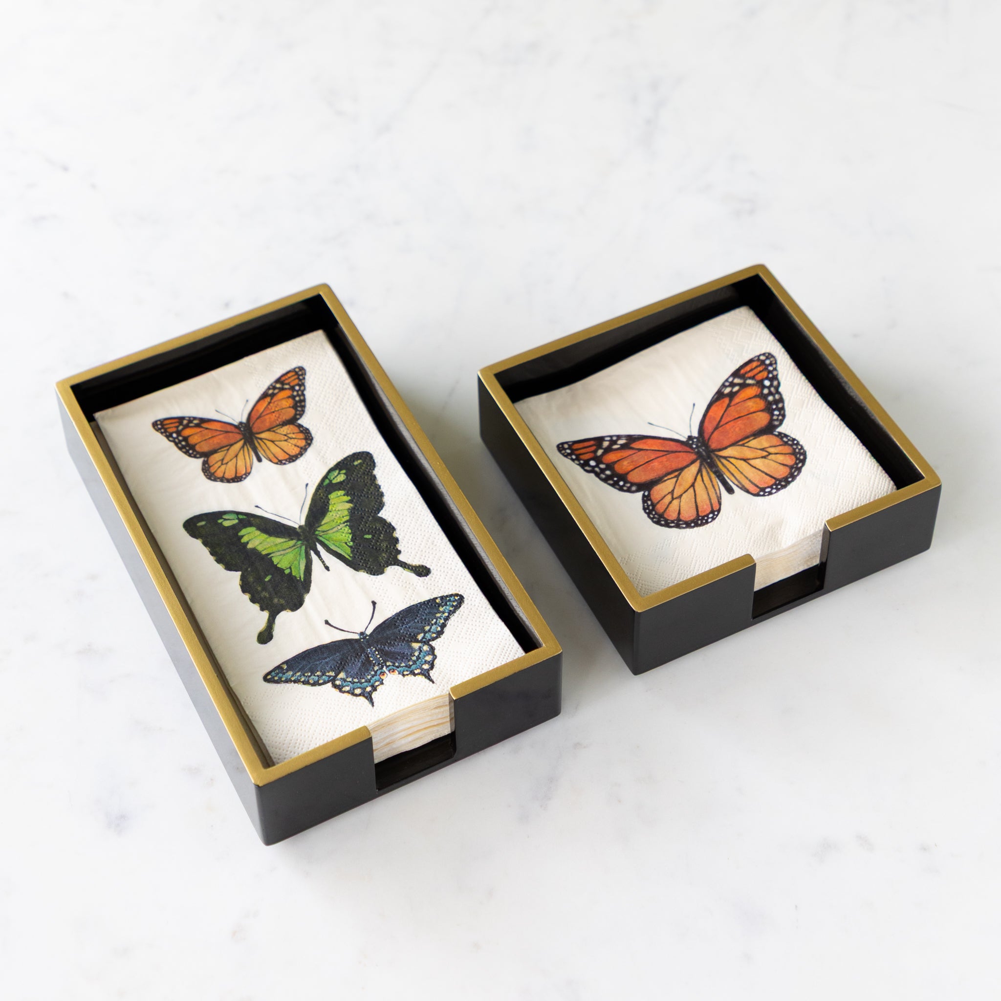 Black Napkin Holders with Gold Trim in a cocktail and guest size with Hester & Cook Butterfly Napkins in them.