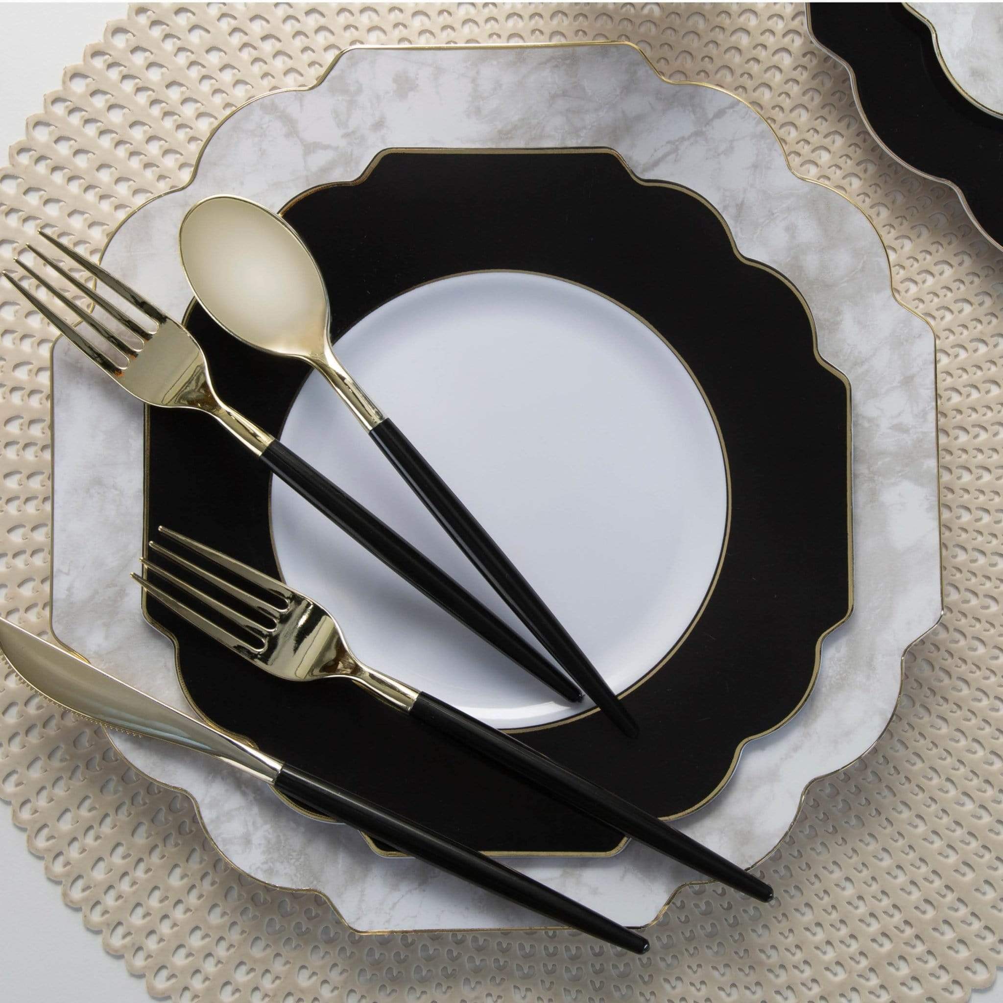 Black and white plate set with gold cutlery on a textured surface.