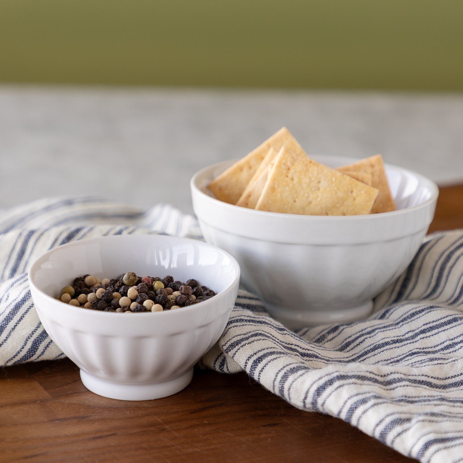 White Fluted Bowls with crackers and peppercorns in them. 