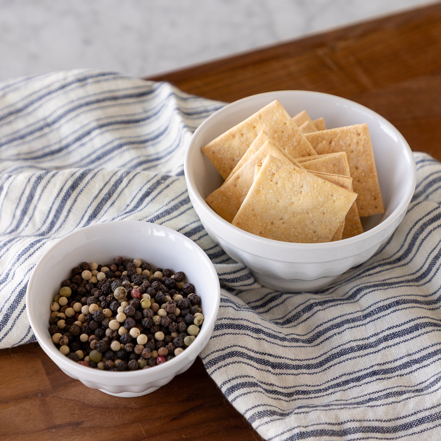 White fluted bowls with crackers and peppercorns in them. 