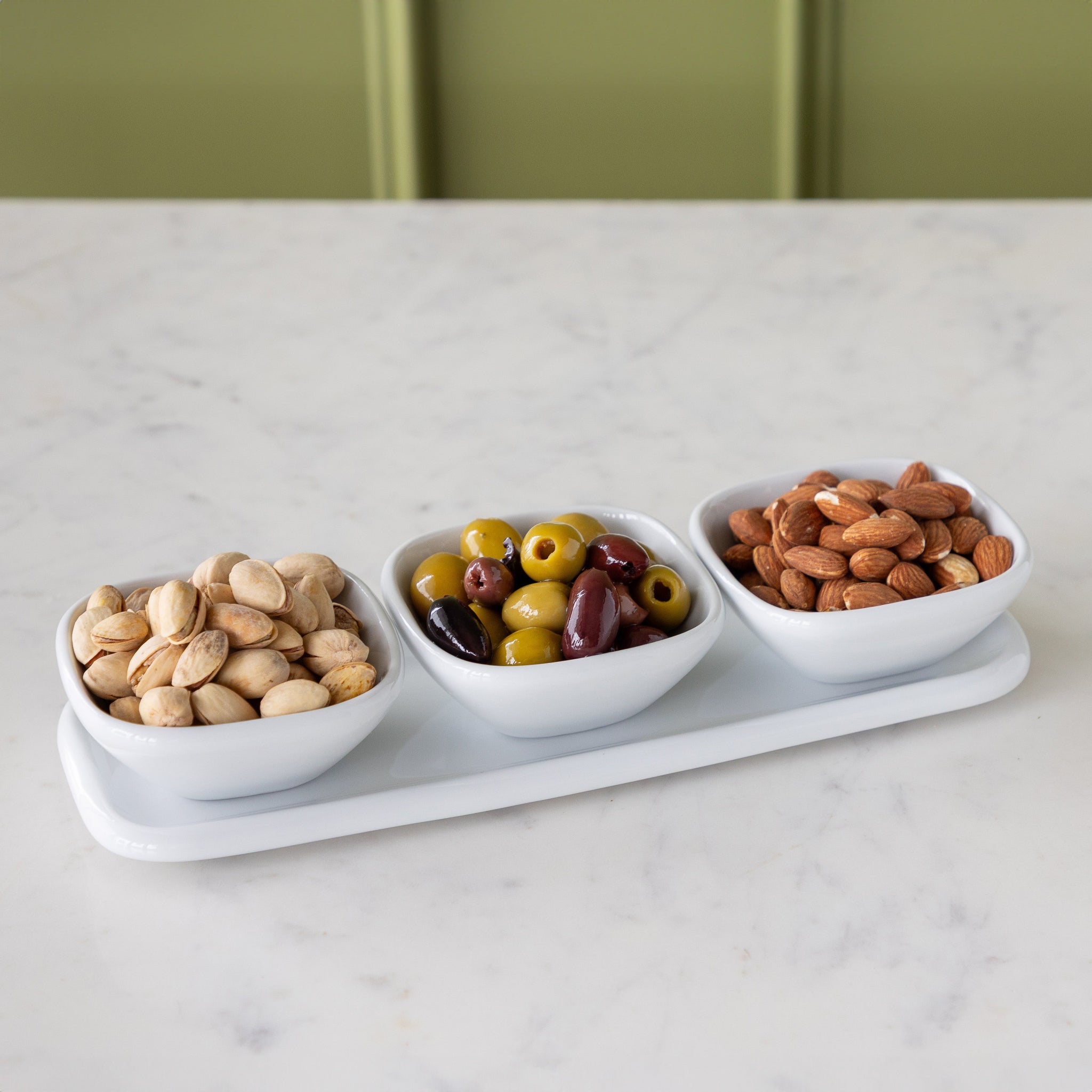 White Porcelain Dip Set featuring three white bowls with nuts & olives on a tray.