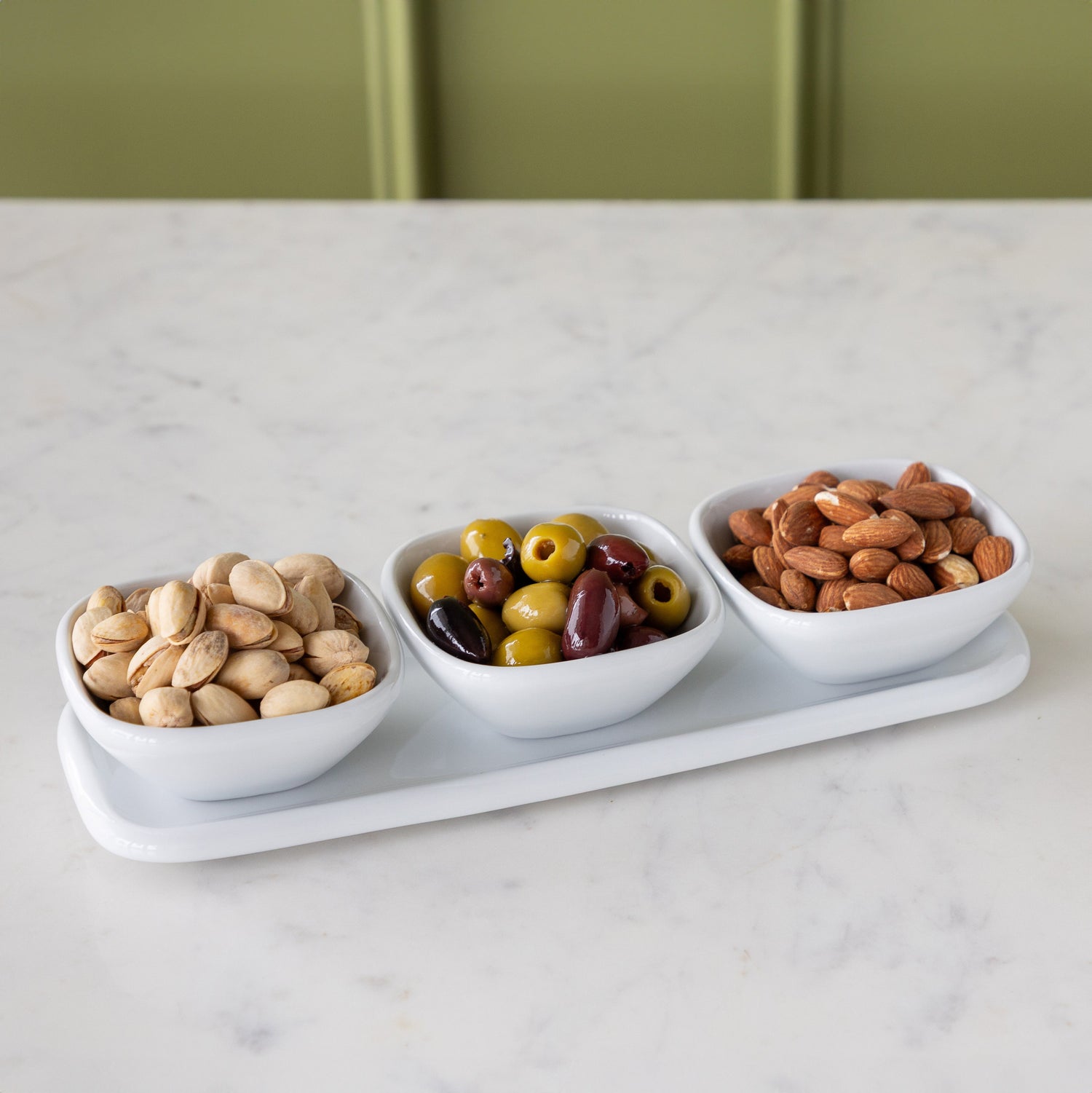 White Porcelain Dip Set featuring three white bowls with nuts &amp; olives on a tray.