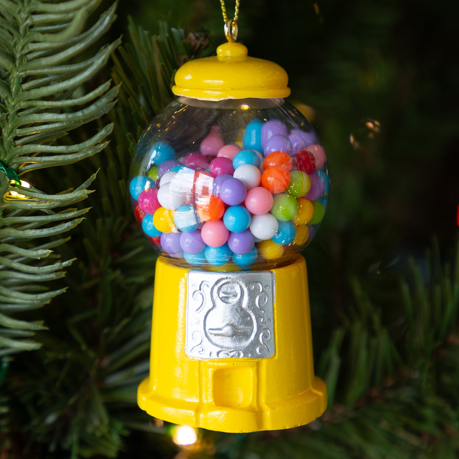 Colorful mustard gumball machine ornament on a Christmas tree.