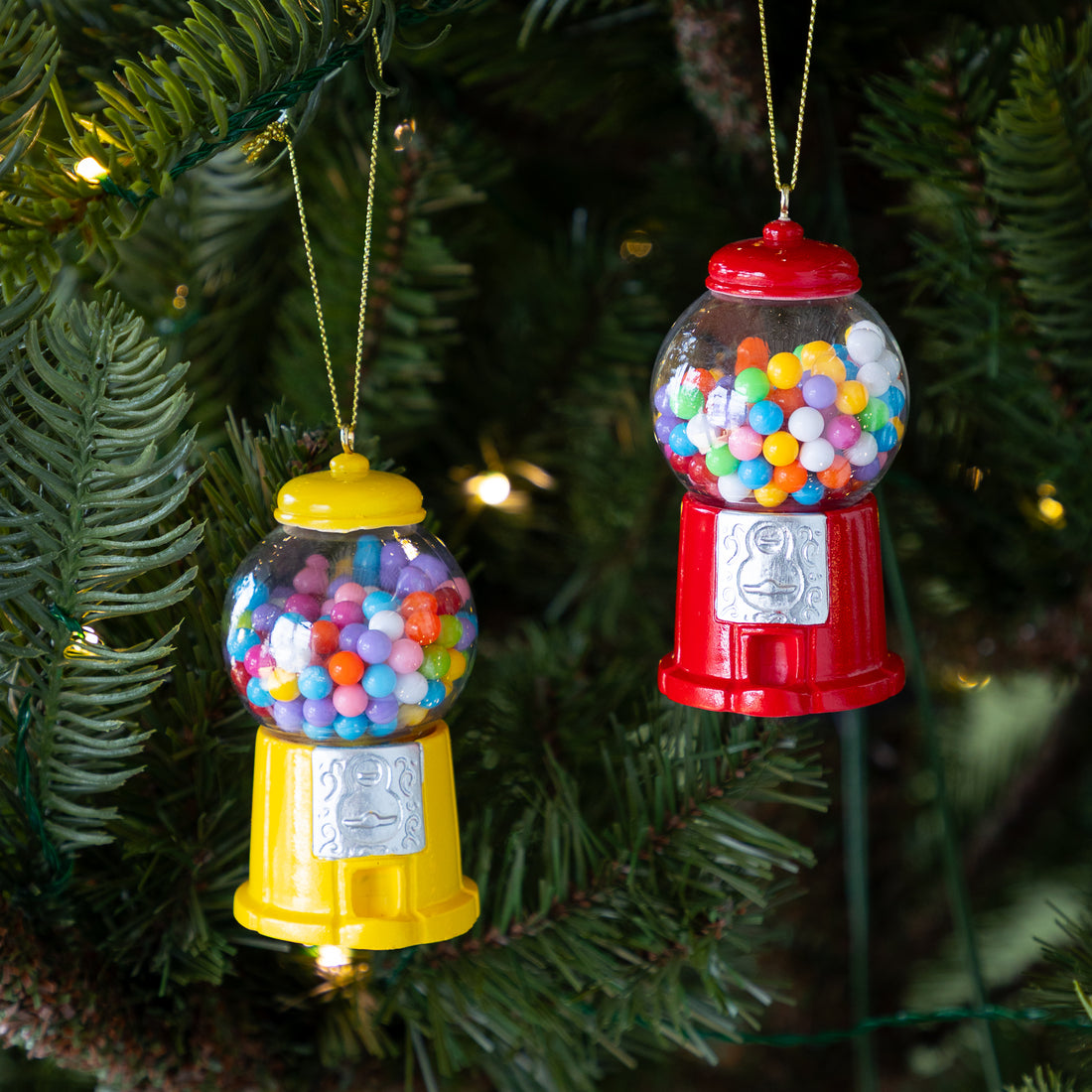 Two gumball machine ornaments hanging on a Christmas tree.