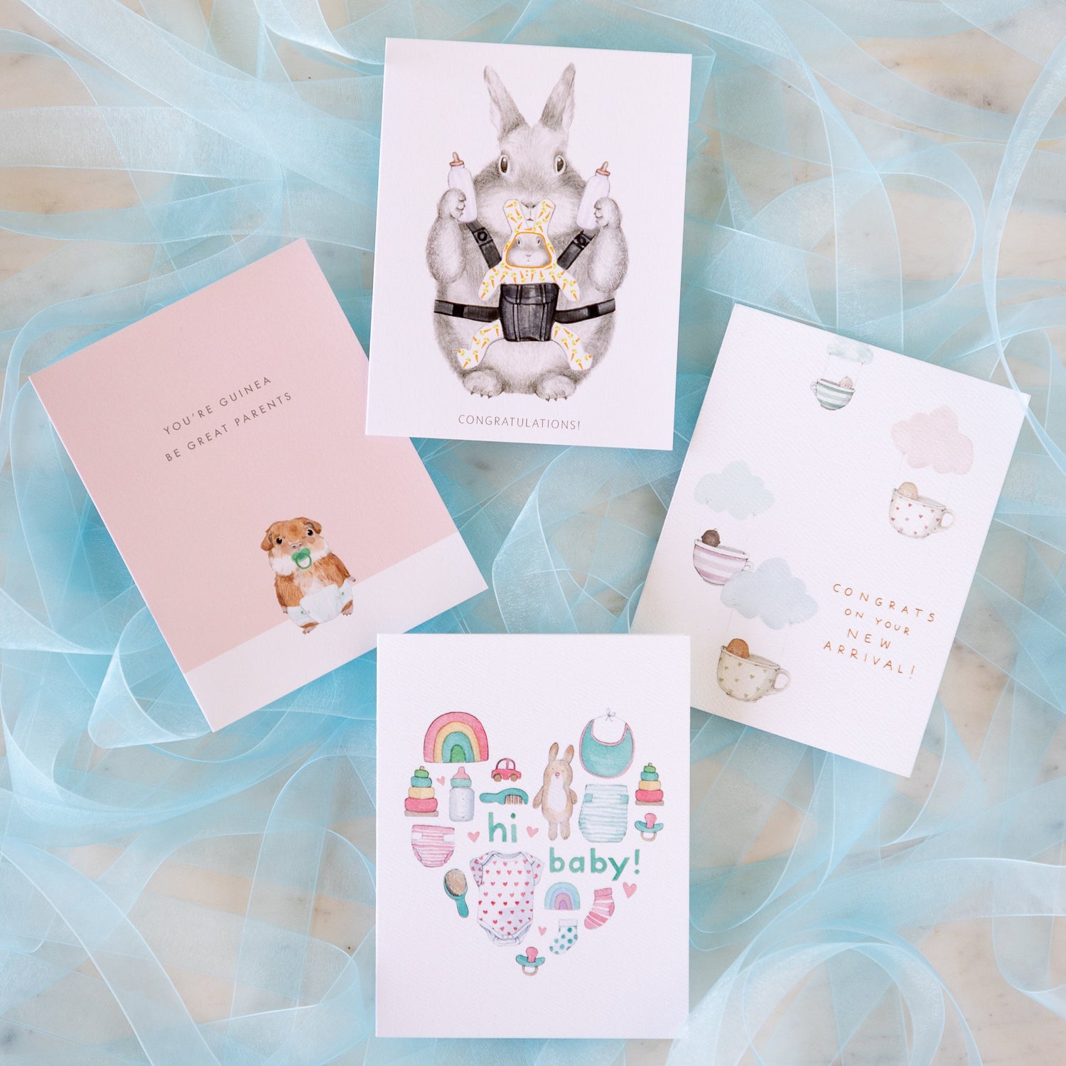 Baby cards arranged on a table on top of blue mesh ribbon.